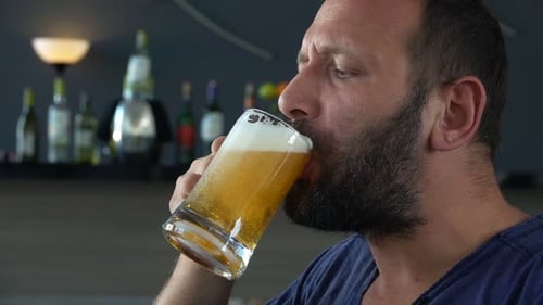 Beau jeune homme apprécie joyeusement une bière rafraîchissante dans un café au ralenti