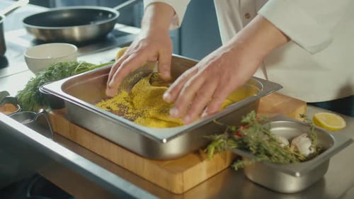 Close Up of Dipping Fish in Corn Meal Mixture Coating All Sides of Fish