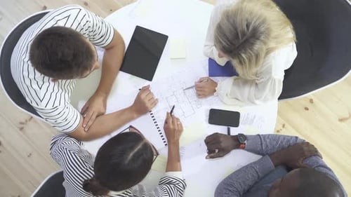 Team Collaborates Over Blueprint in Modern Office