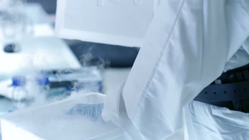Medical Virology Research Scientist Works in a Hazmat Suit with Mask, She Inspects Test Tube with I