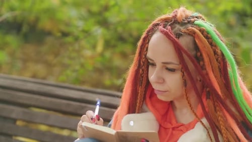 Woman with Dreadlocks Writing in a Notebook
