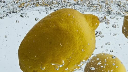 Fresh Lemons Immersed in Bubbling Water, Close Up