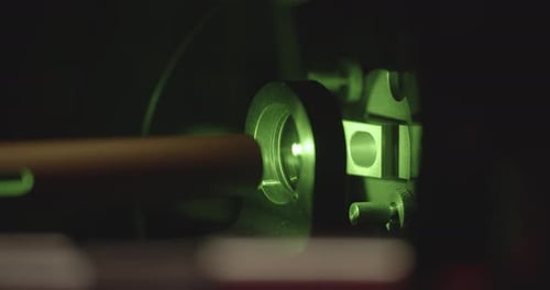 Close up shot of green laser projector lighting in dark room. Presenting vintage film in school.