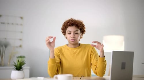 Young Woman Sits at Workplace at Table with Laptop in Home Office and Meditates Closing Her Eyes and