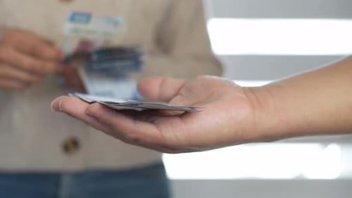 Hands Counting and Giving Mexican Pesos Indoors