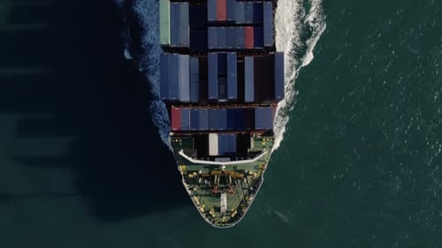 Aerial top view of a loaded container cargo vessel traveling over ocean.