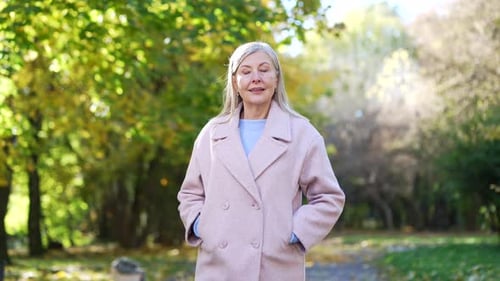 Happy senior gray haired woman walking in park, smiling outdoors Elderly older lady retired female