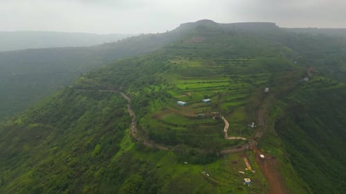 Aerial view of vehicles on Panchgani ghat road, lush green mountains and monsoon sky create magic