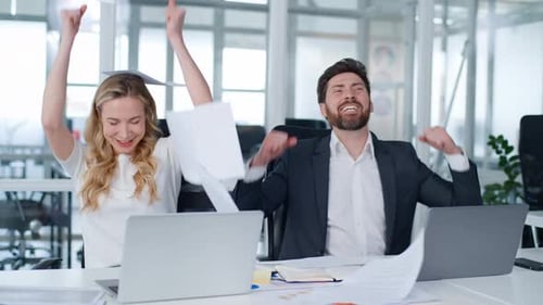 Two Business Partners Throwing Papers in Air Happy Partnership at Office Table Caucasian Middleaged