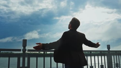 Man Enjoying a Peaceful Moment By the Waterfront Under a Cloudy Sky