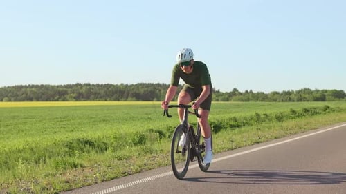 Cyclist Rides Through Rural Landscape on Sunny Day