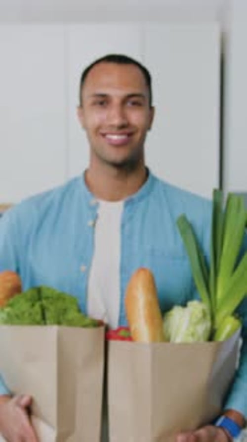 Smiling Man Holding Groceries in Paper Bags Indoors
