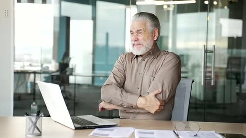 Senior Man Experiencing Elbow Pain at Desk
