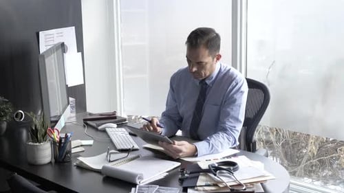Doctor reviews patient data on digital tablet at clinic office during the day