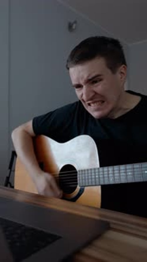 Vertical of Disappointed Man Fails Playing Guitar Watching Tutorial