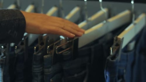 Hand Browsing Jeans in Clothing Store Close Up