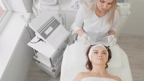 A Beautiful Woman Receives a Microcurrent Facial Skin Treatment From Cosmetologist in a Spa Salon
