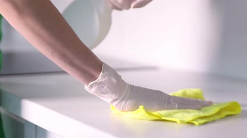 Person Cleaning White Surface with Spray and Cloth