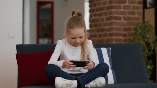 Excited Girl Playing Mobile Game on Couch