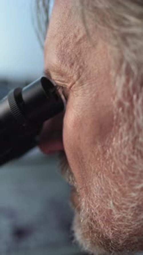 Imagem aproximada de um microbiologista maduro analisando amostras fósseis sob microscópio