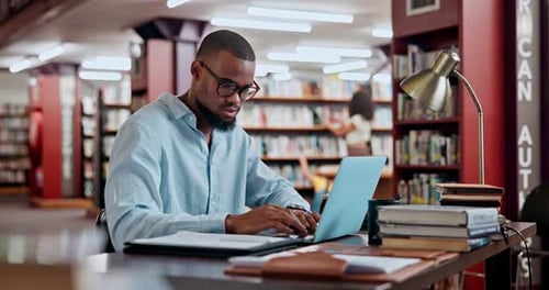 Man, laptop and library studying for university research or project deadline as scholarship