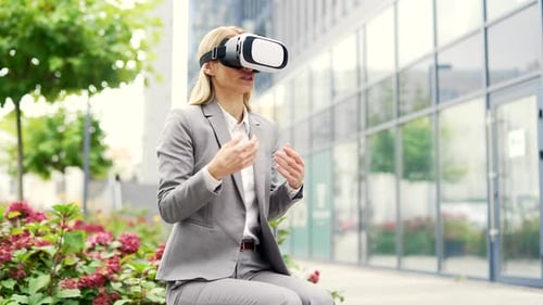 Businesswoman in formal suit using VR glasses for video call and chatting online in virtual reality