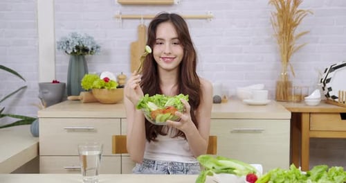 Young Woman Enjoys Healthy Salad in Bright Kitchen