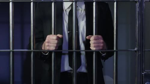 Criminalité en col blanc : zoom lent sur les mains d'un homme d'affaires dans les barreaux de prison HD