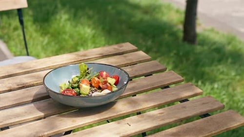 Closeup in Restaurant on the Street on a Wooden Table the Chef Puts on the Table a Blue Plate with a