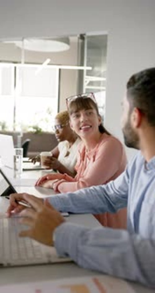 Vertical video: Colleagues in office discussing work, using laptops and taking notes