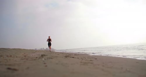 Athletic Sporty Woman on a Morning Jog on the Ocean Shore