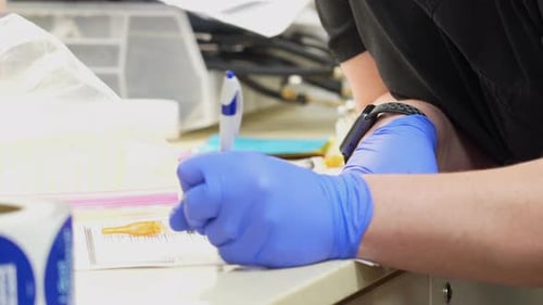 Medical Worker Writing on Paper with Syringe