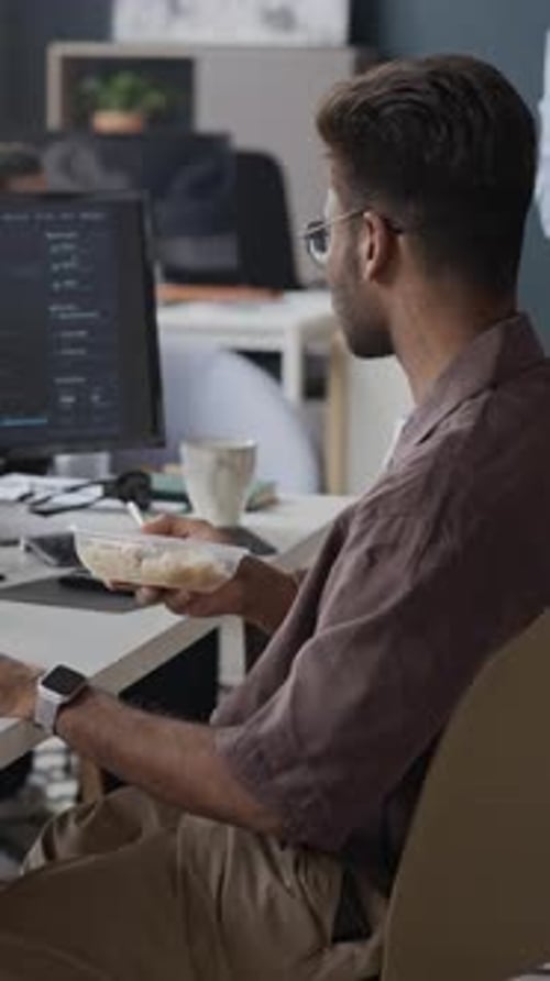 Indian Male Software Developer Eating Lunch at Desk in IT Office