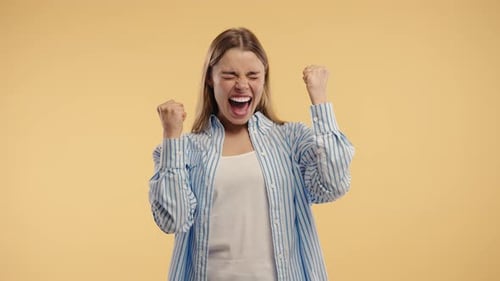Excited Woman Celebrates Success on Yellow Background