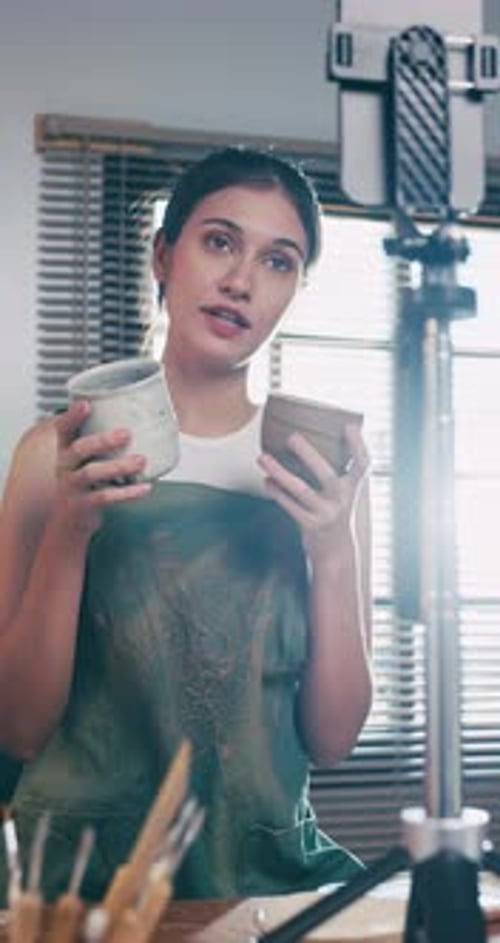 A female ceramicist is teaching about pottery in the workshop online.