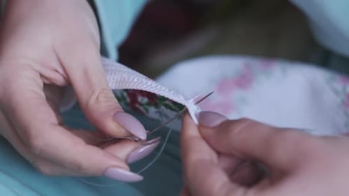 Hands Sew Floral Fabric with Needle and Thread