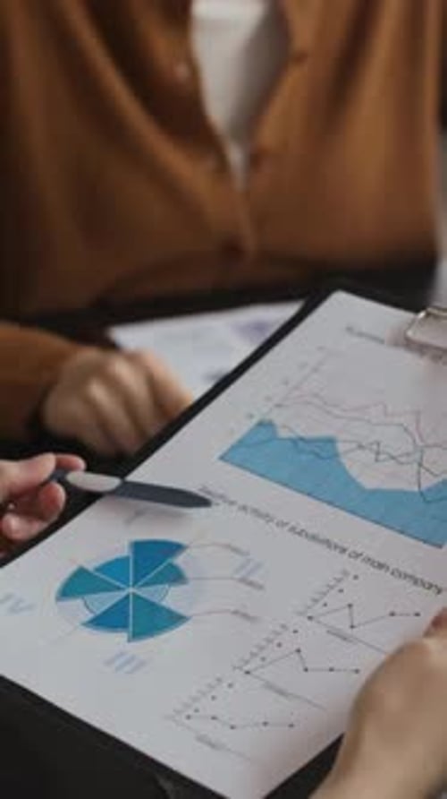 Anonymous Employees Analyzing Financial Papers at Office Table