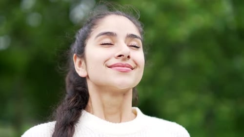 Close up portrait young happy woman standing in nature between forest trees relaxes, breathes fresh