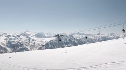 Ski lift high in the mountains captured by drone during the winter with skiers going on top