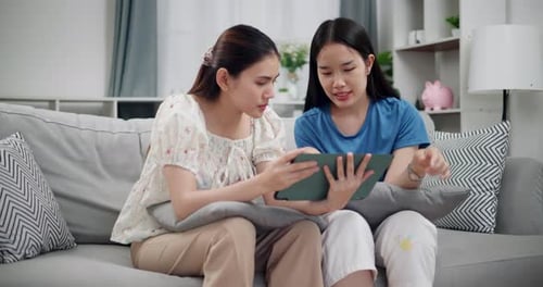 Young Women Using Tablet Together on Sofa