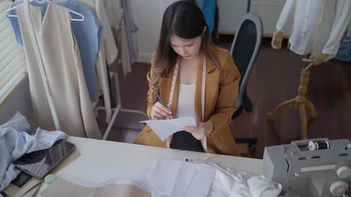 Fashion Designer Tracing Patterns at Her Workspace