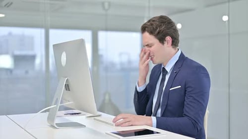 Shocked Young Businessman Reacting to Failure on Desktop in Office