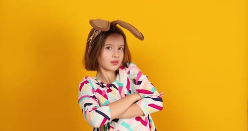 Happy playful teenager girl wearing bunny ears on a bright yellow studio