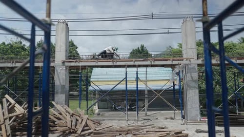 Vista a través de andamios de un trabajador manual que ata barras de refuerzo en una plataforma elevada en el sitio de construcción