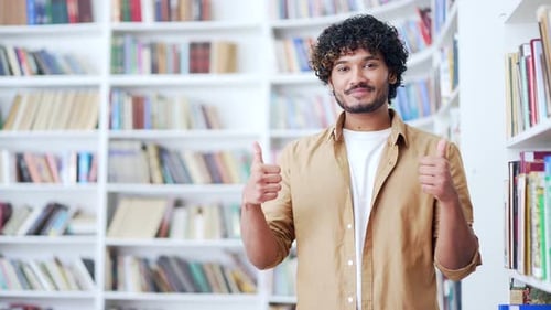 Portrait of young smiling university student showing thumbs up looking at camera. Happy positive
