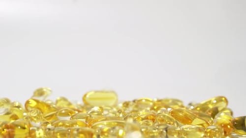 Transparent golden pills falling on white background. Oil pills capsule Skin care medical Europe 4k