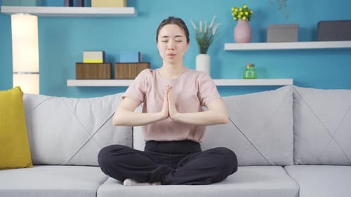 Woman Meditating in Lotus Position on Couch