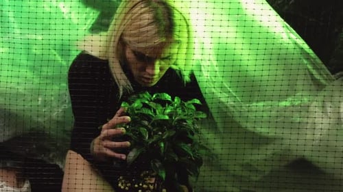 Woman Looks at Plant Through Net and Plastic