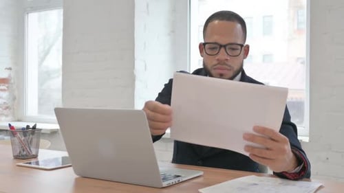 Professional Man Reviews Documents at Modern Office Desk