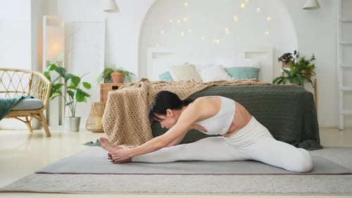 Woman Stretching Legs on Exercise Mat Indoors